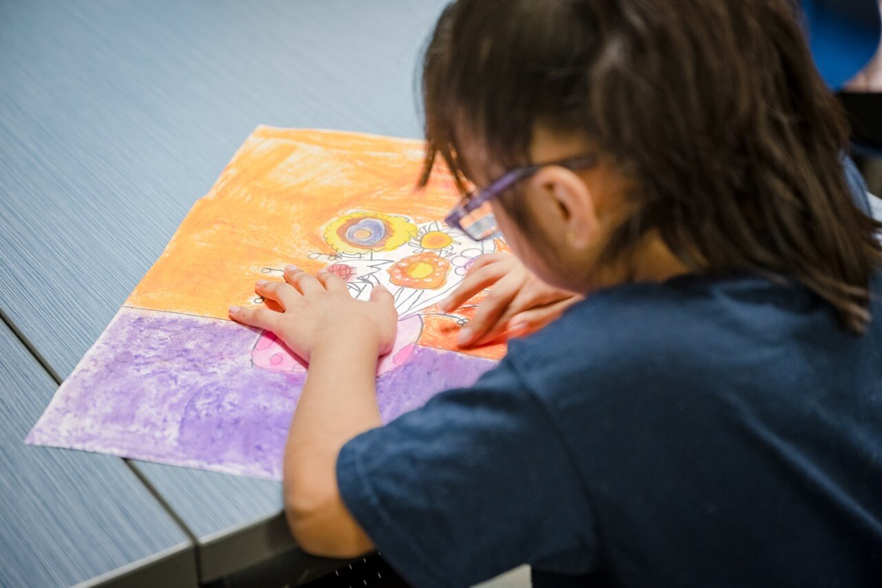 Enfant dessinant en violet et orange